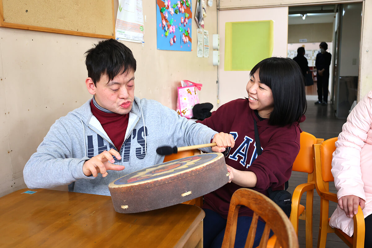 太鼓を叩く利用者さまと女性スタッフの様子